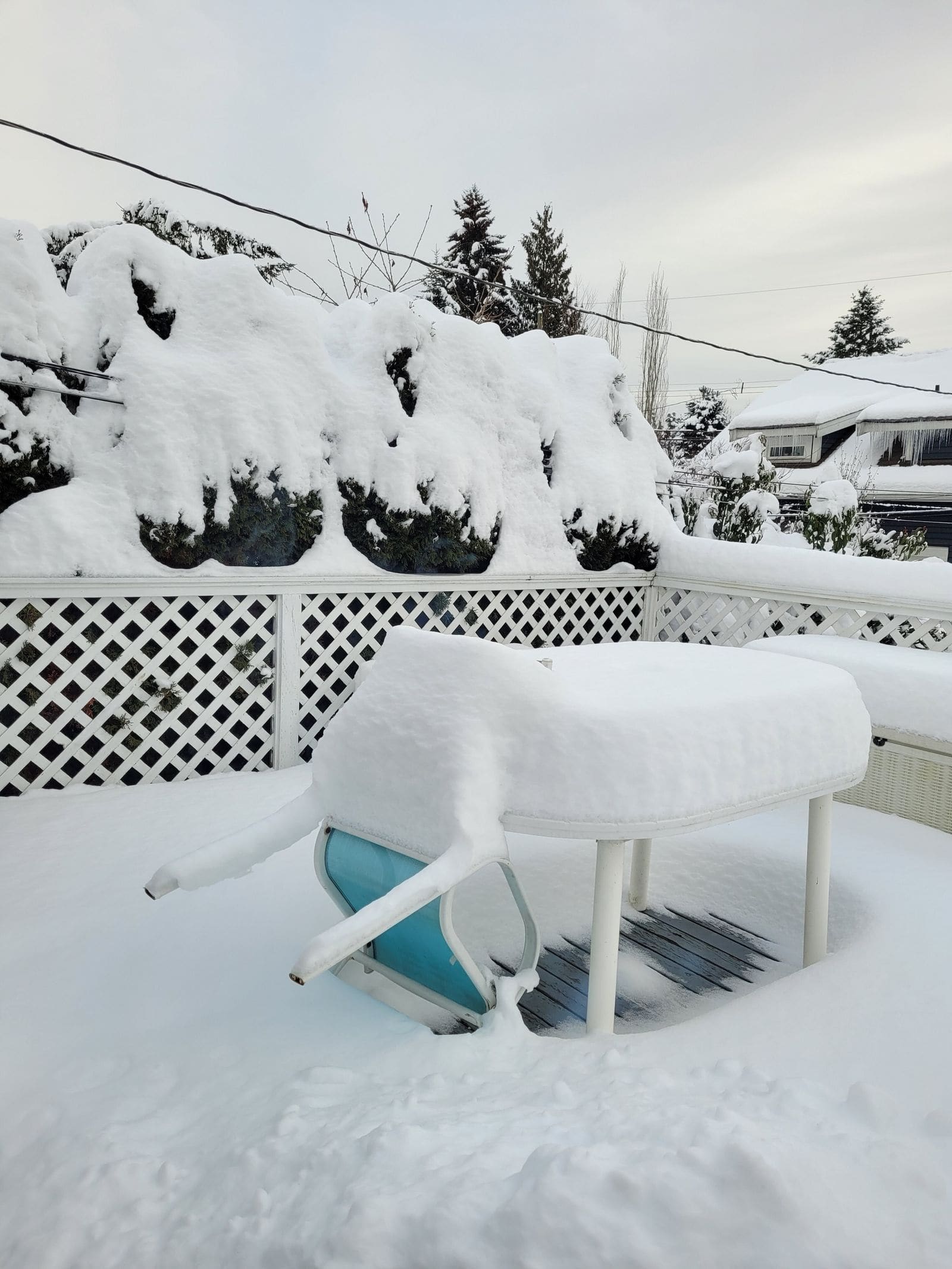 Patio table and chair buried in snow on a backyard terrace